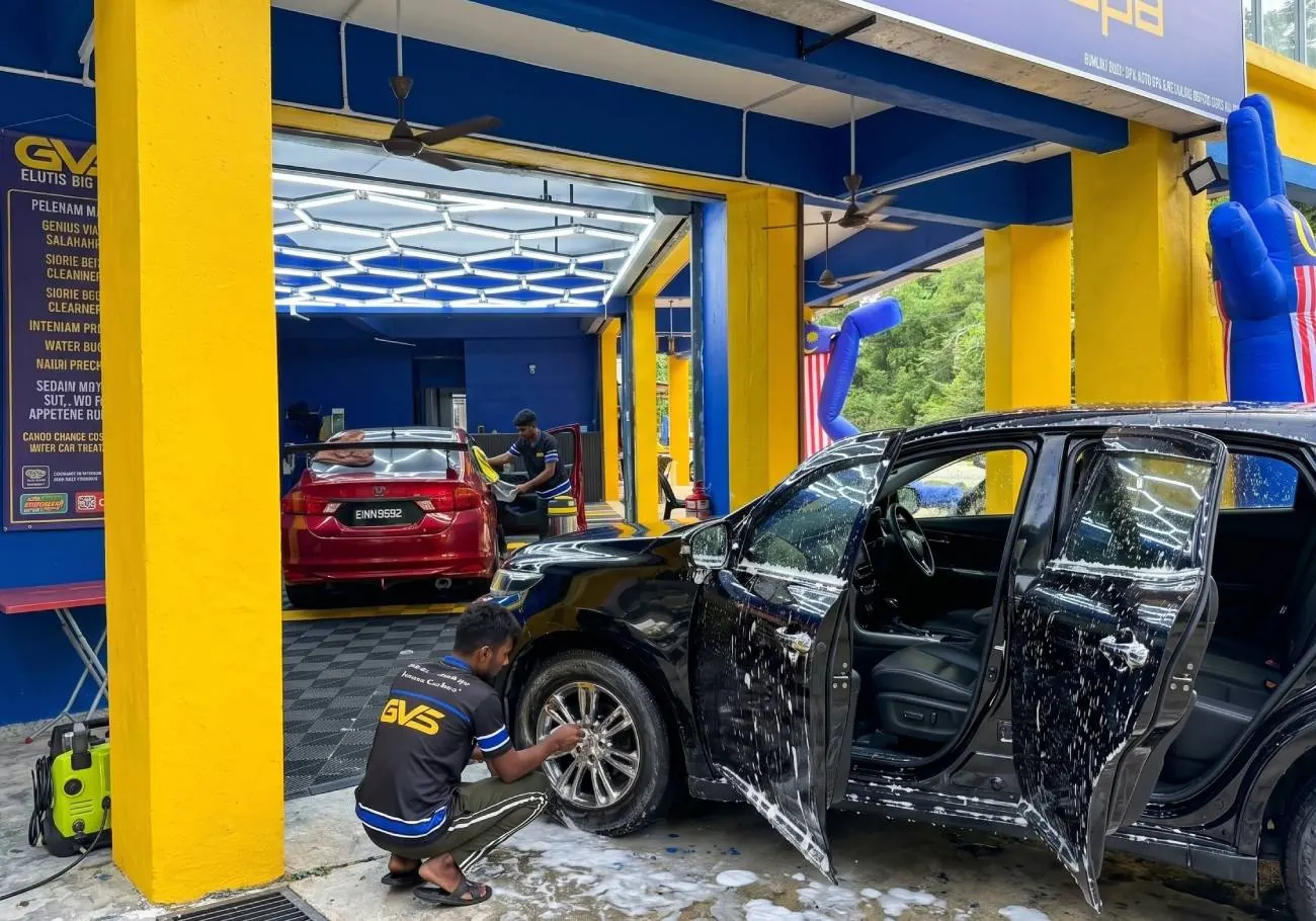 An MPV covered in foam being washed at the shopfront bay